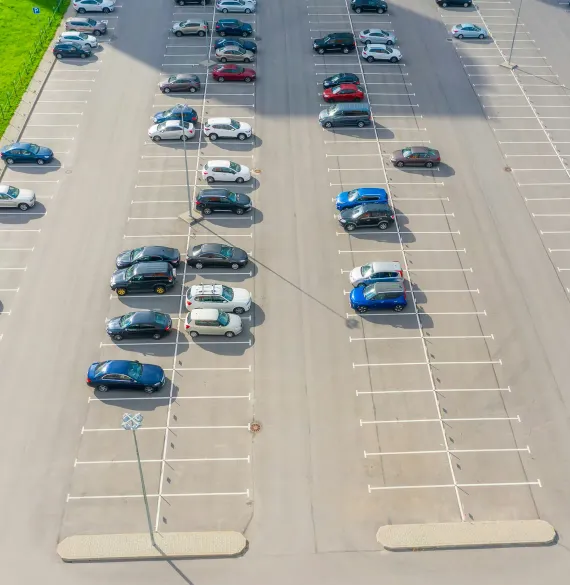 A part-filled surface car park seen from above, with long rows of marked bays