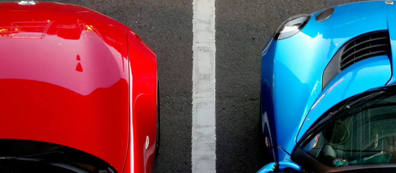 Two parked cars photographed from above, their bonnets either side of a white bay line